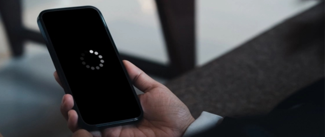 Hand holding smartphone with loading screen indoors