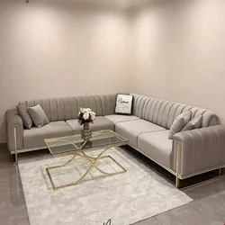 Modern grey L-shaped sectional sofa with vertical tufting and a glass coffee table in a minimalist living room